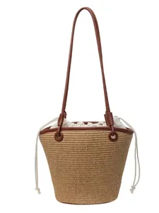 Straw woven bucket bag with brown leather straps and white drawstring inner lining