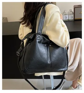 Detail of black tote bag with lychee texture, silver studs, and detachable shoulder strap