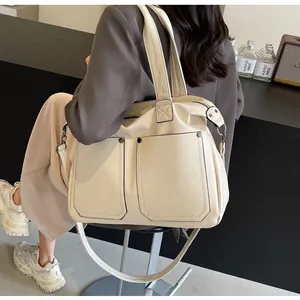 Detail view of cream tote bag featuring dual front pockets and black edge finish
