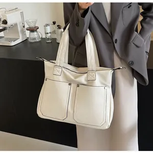 Close-up of beige PU leather tote bag with dual front pockets and metallic zippers