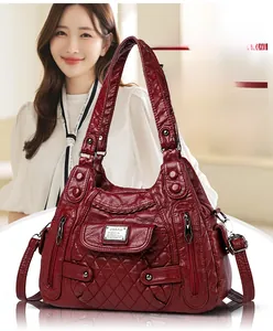 Macro detail of red quilted soft leather handbag with dual handles and metal zipper pockets