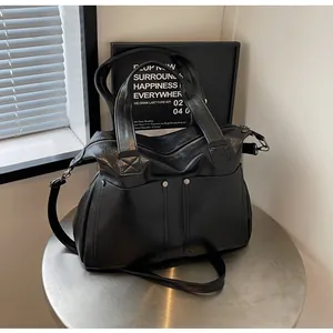 Close-up of vintage black tote bag with silver rivets and large pockets on metal table