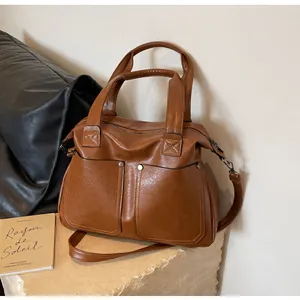 Macro shot of brown faux leather tote bag showing fine texture and silver metal buckles