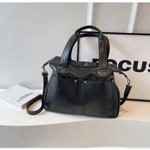 Detail of black PU leather tote bag with silver buckles and adjustable shoulder strap
