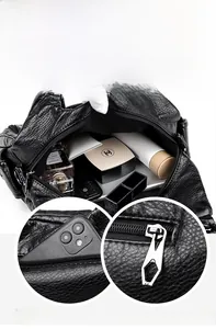 Macro view of black litchi grain leather bag showing spacious compartments and zip pocket
