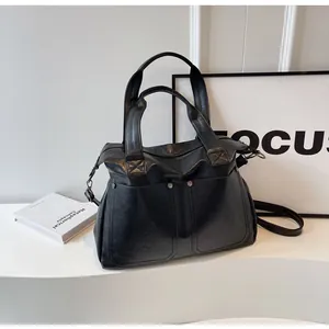 Detail of a vintage black tote bag featuring double front pockets and metallic rivets