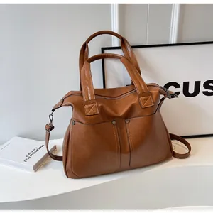 Detail view of brown vintage tote bag with twin front pockets and metallic rivets
