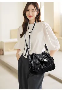 Detailed macro view of black quilted faux leather handbag with multiple zipper pockets