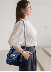 Detail of navy blue quilted leather bag with multi-pocket design and metal logo