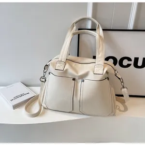 Detail view of cream-white tote bag with functional pockets and rivet studs