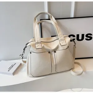 Detail of a creamy white large tote bag with symmetric pockets and detachable strap