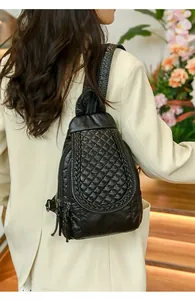 Close-up of quilted black faux leather backpack with woven trim and tassel zipper detail