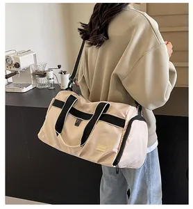 Detailansicht der cremefarbenen Reisetasche mit schwarzen Gurten in einem Café
