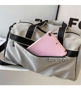 Detail view of the front zipper pocket on light gray gym bag holding a tablet