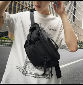 Detail of a large black crossbody bag with multiple zip compartments and adjustable wide strap