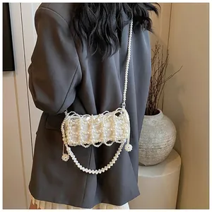 Détail d'un sac à bandoulière en perles fait main porté sur une veste de blazer grise