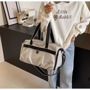 Detail der hellgrauen Reisetasche mit schwarzen Gurten, getragen von einem Modell