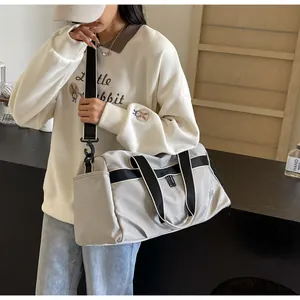 Details einer grauen Reisetasche mit schwarzem Schultergurt und robuster Textur