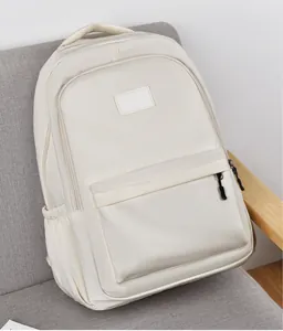 Détail d'un sac à dos blanc cassé minimaliste avec poche zippée sur canapé gris