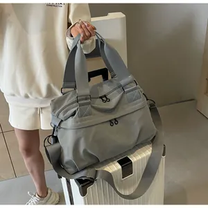 Detail einer grauen Reise-Tragetasche aus Nylon mit verstärkten Griffen auf einem Koffer