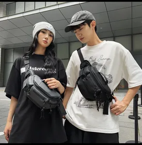 Outdoor city street view of a black tactical crossbody bag with multiple zip pockets