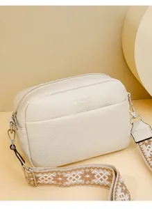 Détail du sac bandoulière en cuir crème avec une large bandoulière tissée à motifs géométriques