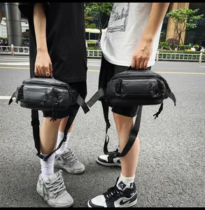 Detail view of the black nylon sling bag's multi-zipper pockets and adjustable strap