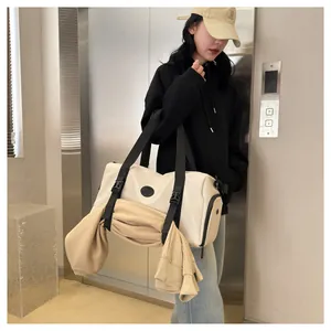 Detail view of cream duffel bag with external straps holding a hoodie for travel use
