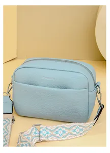 Détail du sac bandoulière bleu clair avec texture cuir grainé et bandoulière à motifs