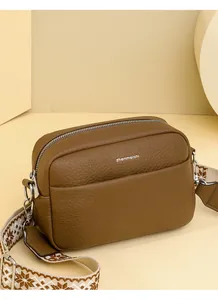 Détail du sac photo marron montrant le cuir litchi et la bandoulière en jacquard