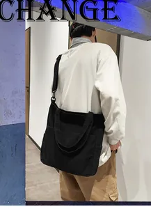 Dettaglio di una borsa tote in tela nera con doppie tasche frontali e tracolla regolabile