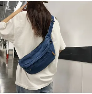 Detailopname van de denim crossbodytas met lederen logolabel en metalen gesp