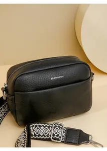 Détail du sac bandoulière minimaliste en cuir noir grainé avec sangle brodée ethnique