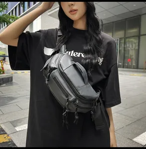 Outdoor street shot of a large black techwear chest bag with multi-zipper compartments