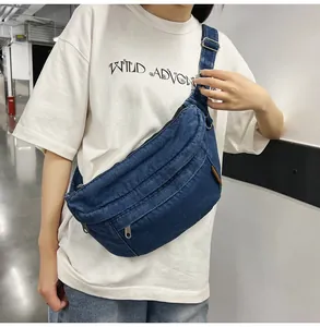 Detailopname van blauwe denim borsttas met meerlaagse ritsen en metalen gespen