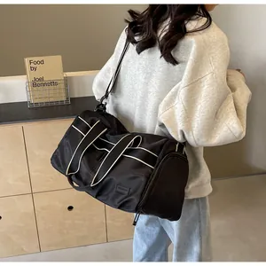 Detail einer schwarzen Nylon-Reisetasche mit beigen Kontrastgriffen und Schultergurt