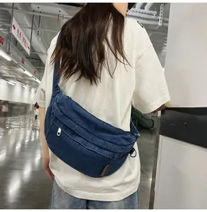 Detail of dark blue denim crossbody chest bag with adjustable strap on a female model