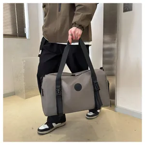 Detail of gray waterproof travel bag with reinforced handles and brand logo patch