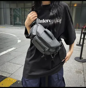 Detail of dark grey utility chest bag showing multiple zipper pockets and waterproof fabric