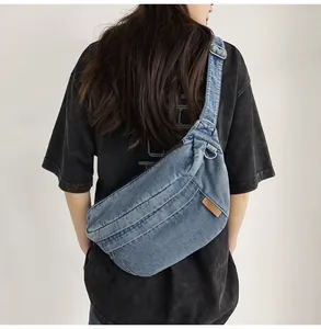 Detail van blauwe denim crossbody borsttas met verstelbare riem en modieus leren label