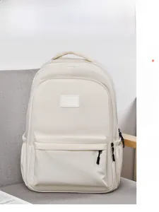 Sac à dos en nylon beige avec grand compartiment principal sur un canapé moderne