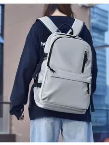 Rear view of a light grey water-resistant backpack with multi-pocket design on model