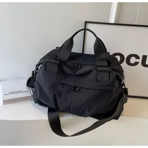 Details einer schwarzen Nylon-Tasche mit verstärkten Griffen und verstellbarem Gurt