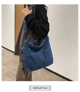 Dettaglio borsa tote in denim blu con due tasche frontali e gancio in metallo nero