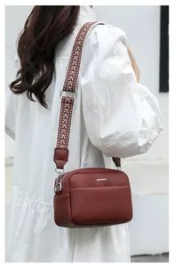 Détail du sac à bandoulière bordeaux en cuir grainé avec une sangle tissée à motifs