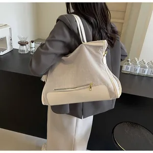 Detail of canvas tote bag showing the contrast faux leather stitching and front zipper pocket