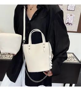 Detail of white lychee leather bucket bag with decorative pearl chain and small pouch