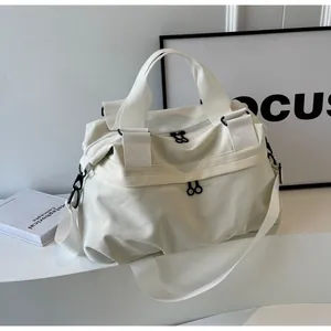 Nahaufnahme der cremefarbenen Nylontasche mit matt schwarzen Reißverschlüssen und Griffen