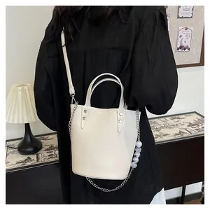 Detailed close-up of cream-colored bucket bag with lychee texture and silver chain