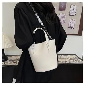 Detail of white lychee leather bucket bag with silver studs and bead chain strap